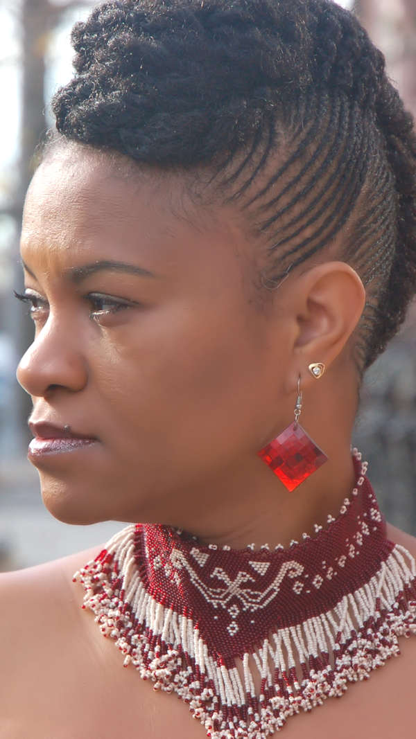 Woman with styled hair in cornrows 4c natural hair using the scalp roller and red earrings, wearing a beaded necklace.