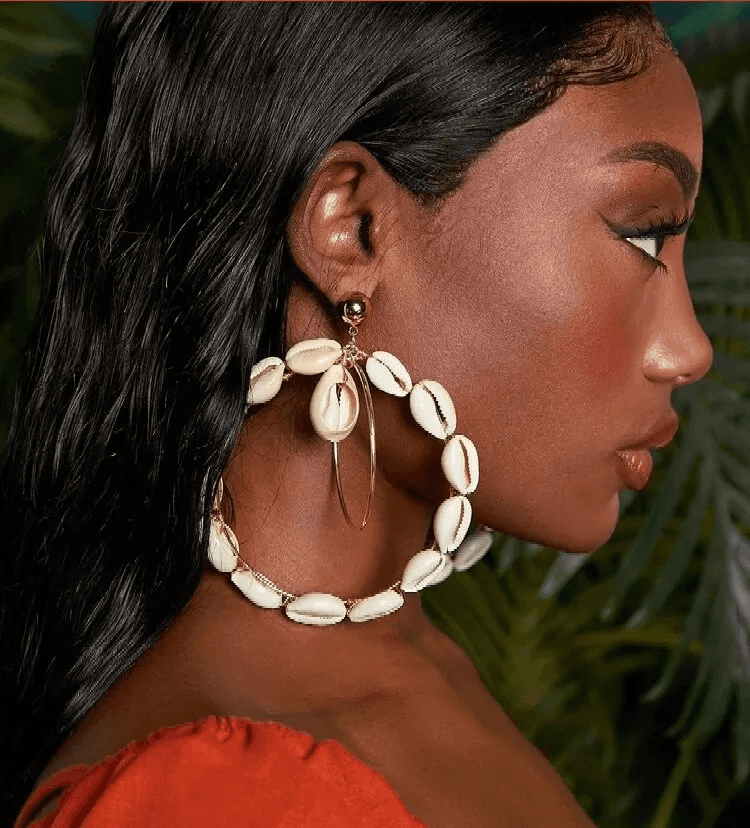 Close-up side profile of a model wearing double hoop Cowrie Shell earrings, highlighting the intricate shell and gold-tone hoop design.