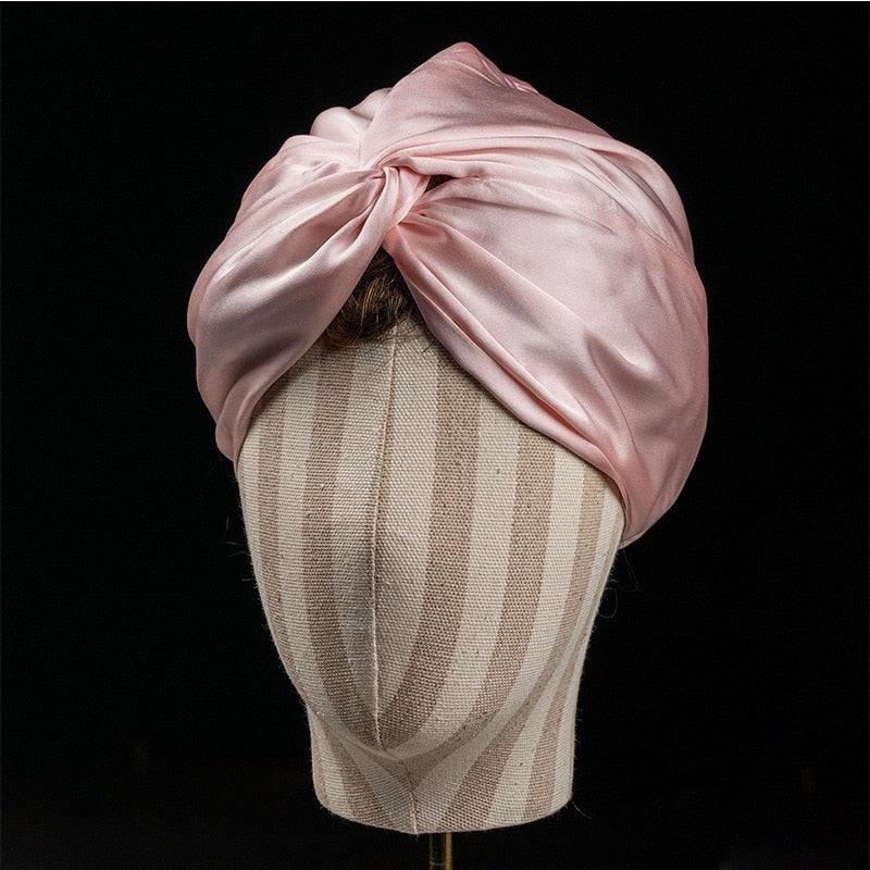 Silk Bonnet Amara De Luxe in soft pink displayed on a mannequin. Made from 100% Mulberry Silk for luxurious hair protection.