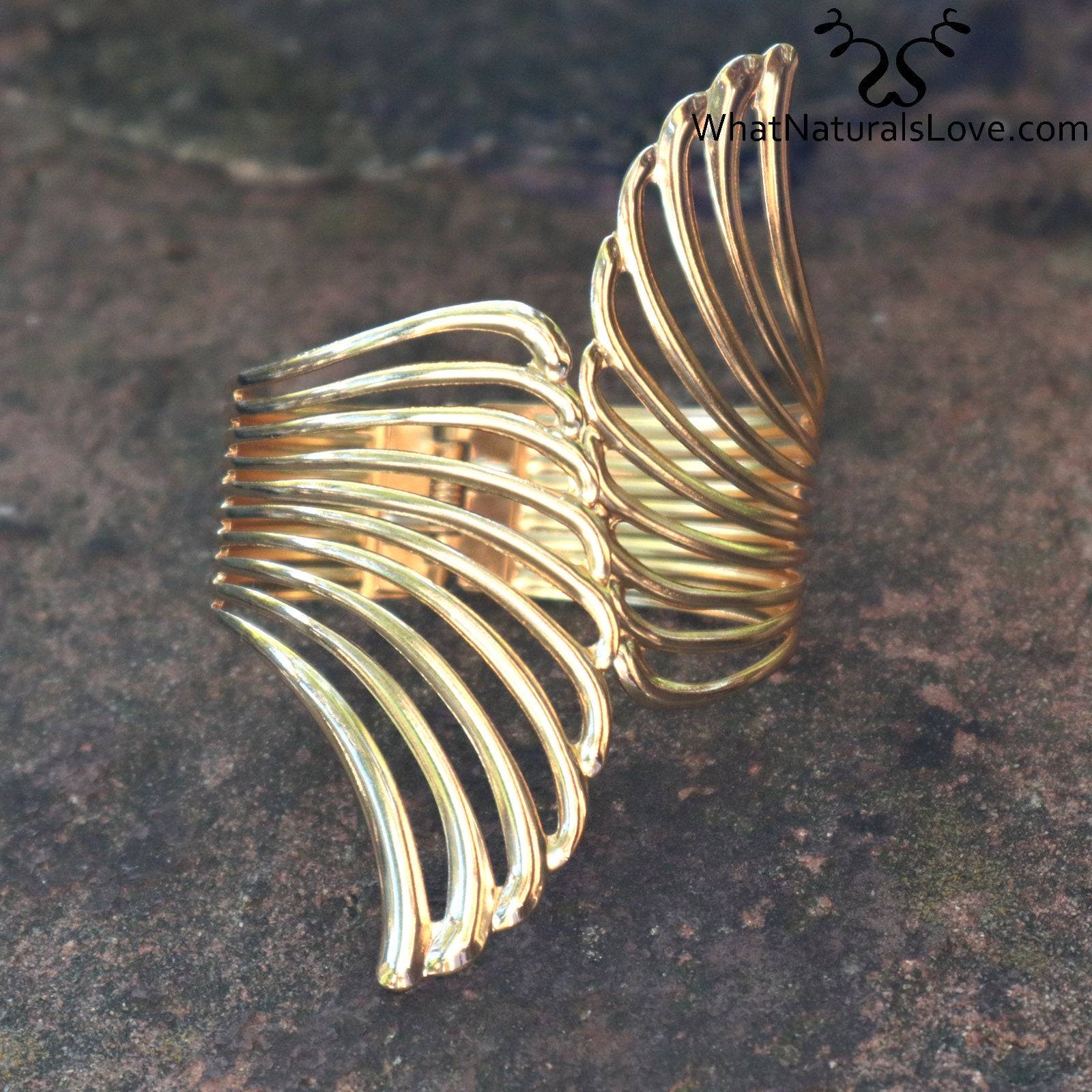 Gold Aurora Wing Cuff displayed on a stone surface, emphasizing its elegant and detailed wing design. Perfect for styling locs and braids.