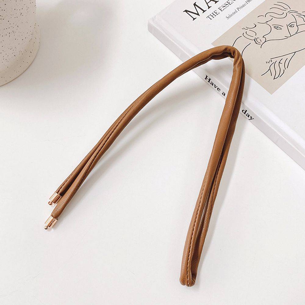 Brown non-damaging ponytail holder for locs laid on a book. Easy-to-use hair tie for dreadlocks, braids, and sisterlocks with gold-tone tips.