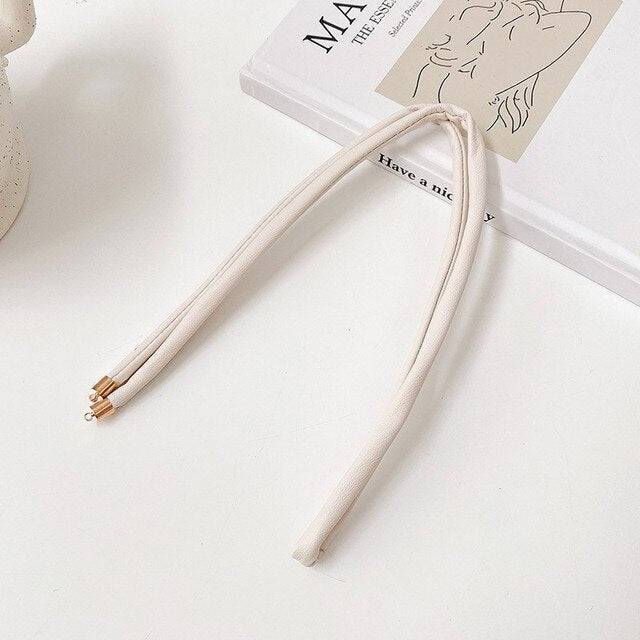 White non-damaging ponytail holder for locs on a white surface. Perfect hair tie for dreadlocks, braids, and sisterlocks with gold-tone tips.