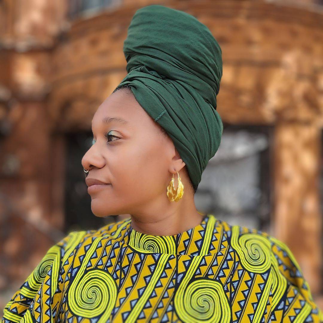 Side profile of a woman wearing a green tube headwrap for locs, sisterlocks, and dreadlocks. A stylish and protective headwear option.