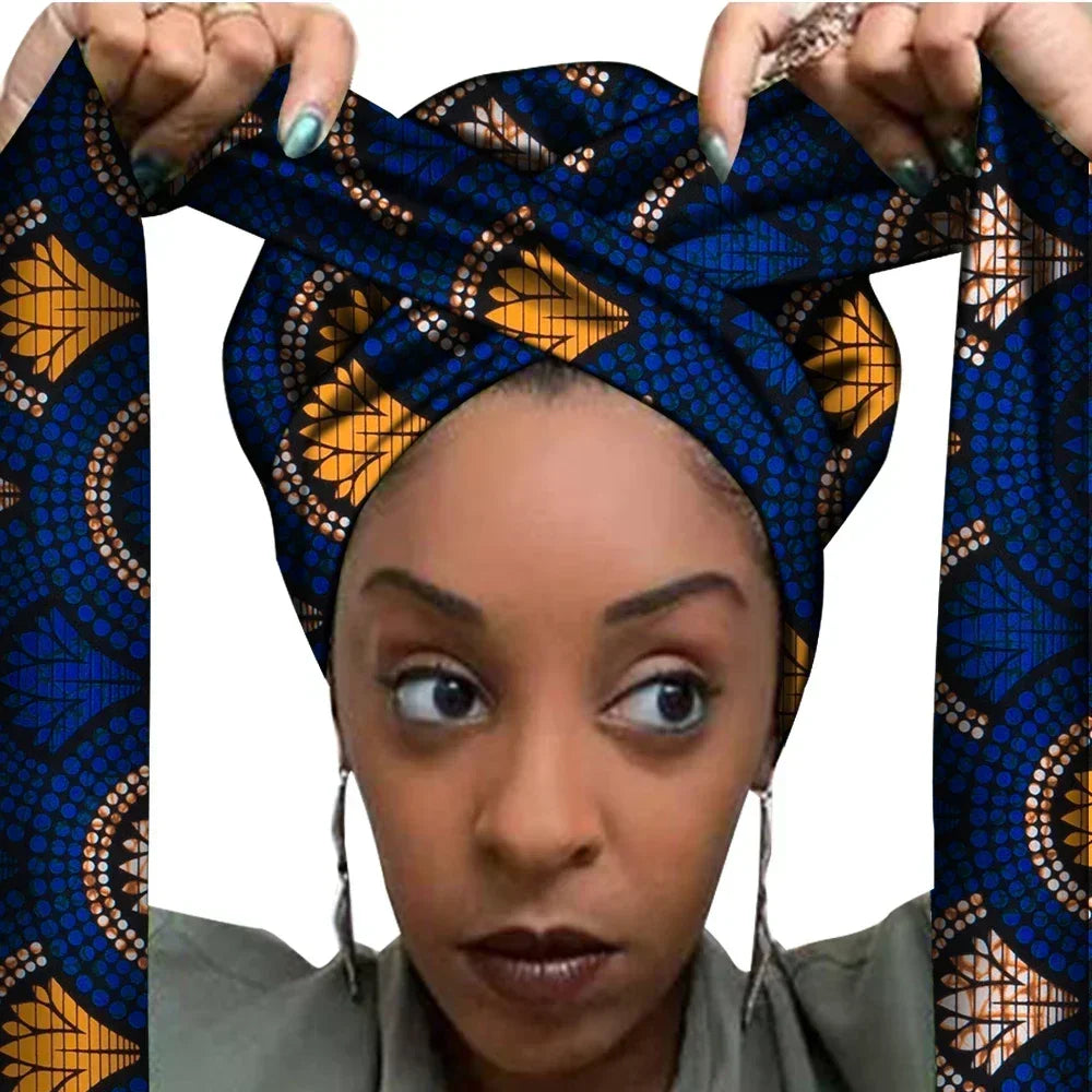 Vrouw met een Afrikaanse headwrap in donkerblauw en oranje Ankara print met geometrisch patroon. De stof heeft opvallende vormen en stippen, met lange linten, handgemaakt van katoen, perfect voor lente en zomer.