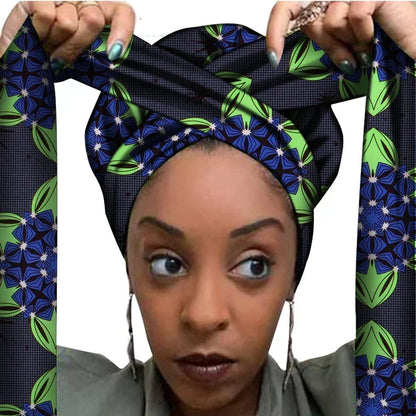 Vrouw met een Afrikaanse headwrap in groen, geel en oranje Ankara print met bruine details. De stof heeft een sierlijk, gedetailleerd patroon met krullen en bloemachtige vormen, lange linten en is handgemaakt van katoen, perfect voor lente en zomer.