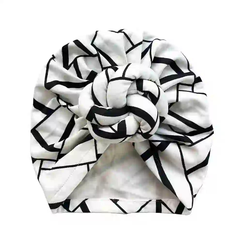 Top view of a black and white geometric patterned knot turban headwrap, highlighting its intricate design and stylish appeal.