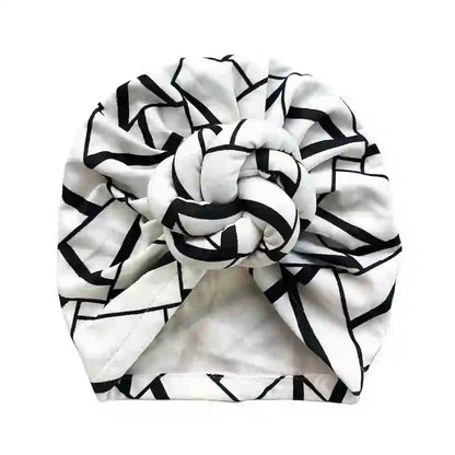 Top view of a black and white geometric patterned knot turban headwrap, highlighting its intricate design and stylish appeal.